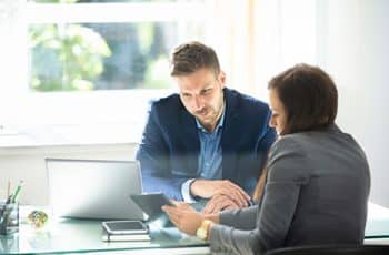 Two Young Businesspeople Using Digital Tablet At Workplace