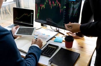 businessman sit at ther table looking at computer laptop in the office , they talking about stock market invest or talk with customer