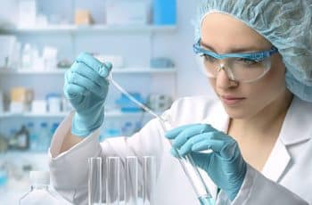 Young female tech or scientist loads liquid sample into test tube with plastic pipette. Shallow DOF, focus on the hand with the tube.